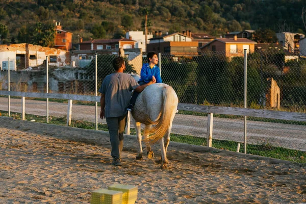 Instructor leading a horse with a child with disabilities at an equestrian center. People with disabilities.