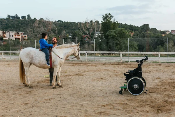 Child with disabilities sitting on the horse while having an equine therapy session. Equine therapy concept.