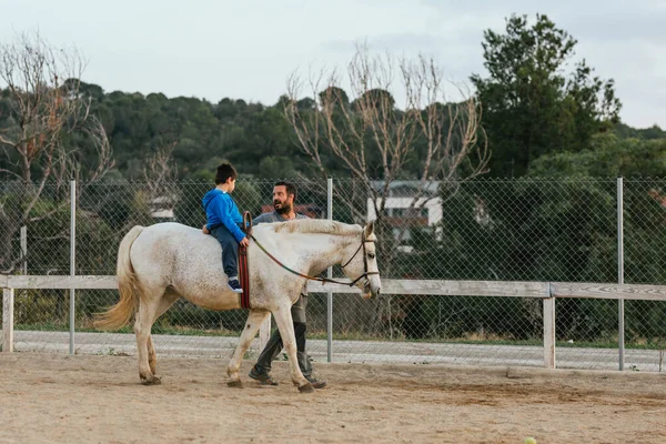 Instructor leading a horse with a child in an equine therapy session. People with disabilities concept.