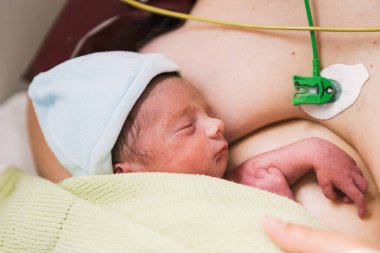 Doğumdan sonra bebeğini kucağında tutan bir annenin yakın plan görüntüsü. Annelik ve doğum kavramı.
