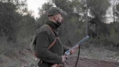 Erkek avcı, doğada dikilirken silah tutuyor. Av sezonu konsepti.