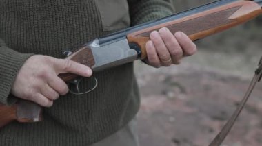 Doğada avlanırken av tüfeği tutan bir avcının yakın görüntüsü. Av sezonu konsepti.