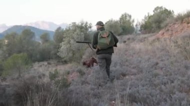 Avcı, av aramak için köpeğiyle yürürken av tüfeği tutuyor. Av sezonu konsepti.