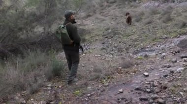 Avcı adam avını köpeğiyle takip ederken av tüfeğini tutuyor. Av sezonu konsepti.