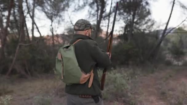 ハンターの男は狩りの銃を手にしながら自然を歩く 狩猟シーズンのコンセプト — ストック動画