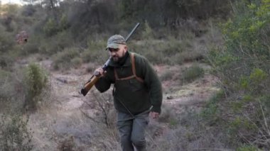 Avcı adam köpekleriyle dışarıda dolaşırken av tüfeği taşıyor. Avlanma kavramı.