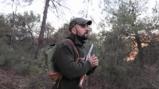 ハンターの男の周りに散弾銃を森の中で屋外に立っている 狩猟の概念 — ストック動画