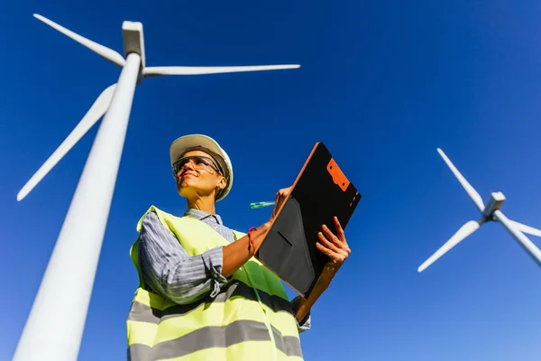 stock image Professional female engineer working in a wind turbine field. Engineering, industry and renewable energy concept.