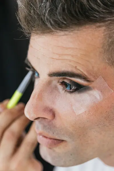 一个同性恋男子独自化妆时投下眼影的垂直特写照片 — 图库照片
