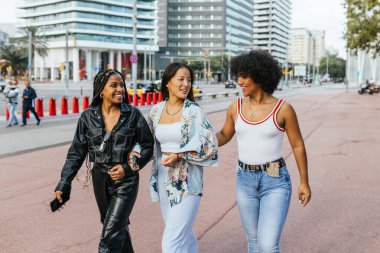 Kadın arkadaşlarıyla şehir caddesinde yürüyen ve konuşan transseksüel bir insan.