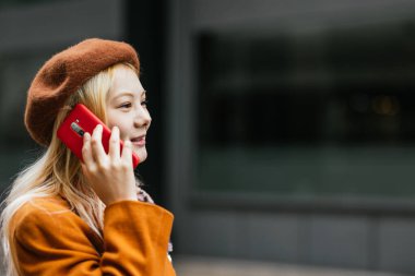 Kapalı alanda telefonla konuşurken yüzünü çeviren şık bir Asyalı kadının yakın görüntüsü. Teknoloji konsepti.