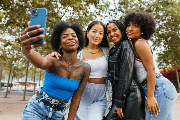 Çok kültürlü kadınlar ve transseksüel insan şehir parkında selfie çekiyorlar.