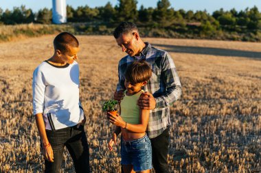 Aile yazın bir tarlada birlikte vakit geçirir, kız bitki yetiştirir ve çevreye yardım eder..