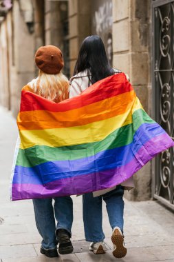 Sokakta yürürken ellerinde Igbt gökkuşağı bayrağı tutan lezbiyen çift. Lgbt kavramı.