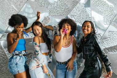 Gri modern bir duvarın yanında kutlama ve dans eden çok ırklı ve çeşitli insanlardan oluşan bir grubun ön görüntüsü.