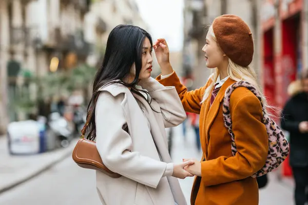 stock image Lesbian couple holding hands and looking at each other while standing on the street. LGBT concept.