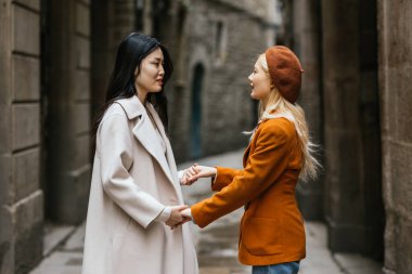 Asyalı lezbiyen çift dışarıda dururken el ele tutuşup birbirlerine bakıyorlar. LGBT kavramı.