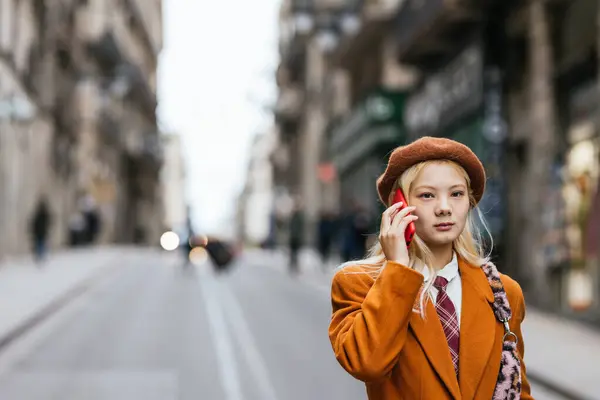 Stylish Asian woman talking on the phone while walking on the street. Technology and urban concept.