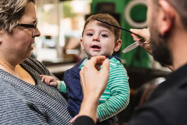 Heartwarming family moment: toddlers first haircut experience at a professional hair salon with a caring parent, gentle hairdresser, and secure safety scissors