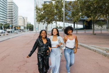 Akşamın erken saatlerinde şehrin bir caddesinde birlikte yürüyen üç neşeli arkadaş. Çok ırklı kızlar birlikte eğleniyorlar..