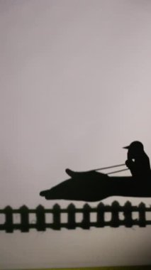 Boş bir arkaplanda ördek kuklası olan büyüleyici gölge kuklası gösterisi geleneksel ve kültürel bir performansta anlamlı bir hikaye anlatıyor.
