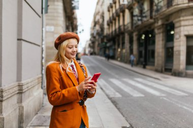 Sokakta dikilirken cep telefonunu kullanan şık Asyalı kadın. Teknoloji ve şehir kavramı.