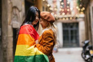 Barcelona, İspanya caddesinde yan yana dururken ellerinde lgbt gökkuşağı bayrağı olan lezbiyen çift. LGBT kavramı.
