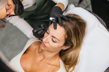 Yetenekli bir makyözün rahat bir kadının yüzüne kozmetik uygulaması güzellik ve estetik hizmetleri yansıtıyor.