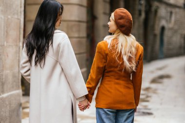 Barselona 'da tarihi binalarla el ele tutuşan iki kadın turist dar bir sokakta yürüyor.