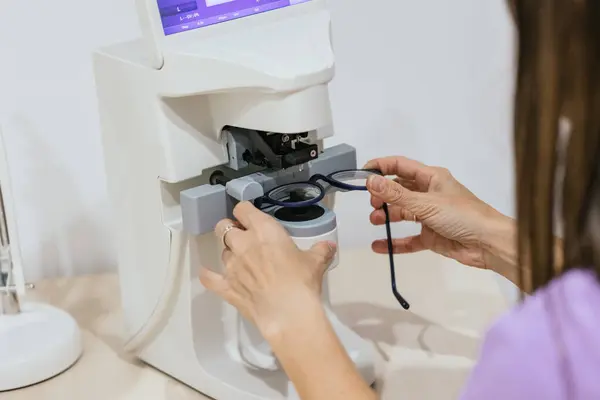 stock image Optician is using a lensmeter to measure the prescription of a pair of eyeglasses