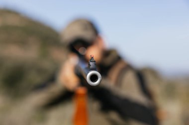 Avcı, av sezonunda ateş etmeye hazır bir tüfekle doğayı hedef alıyor.