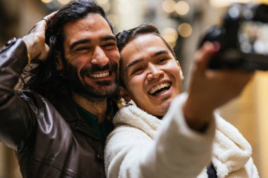 Mutlu eşcinsel çift dijital kamerayla selfie çekiyor, boş zamanlarının ve şefkatlerinin tadını çıkarıyorlar.
