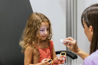 Göz muayenesi sırasında retinoskop kullanan pediatrik optometrist.