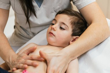 Otojenik drenajı olan bir çocuğa yardım eden fizyoterapist. Solunum yolu açmak için bir solunum fizyoterapisi tekniği.