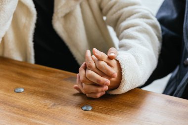 İki adamın ahşap bir masada el ele tutuşması, sevgi, ilgi ve bağın göstergesi.