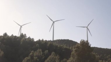 Rüzgar türbinleri tepenin üstünde sorunsuzca dönüyor. Temiz zemine karşı dönen pervanelerle yenilenebilir temiz enerji üretiyor.