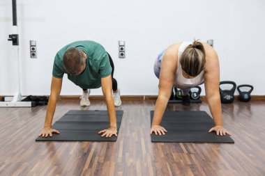 Belirli müşteri ve kişisel antrenör şınav çekiyor, spor salonundaki çekirdek kaslarını güçlendiriyor