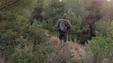 Profesyonel bir avcı kamuflaj kıyafeti giyerek av sezonunda yoğun orman ormanlık alanda eğitimli Brittany Spananiel köpeğiyle birlikte av tüfeğini hedef alır.