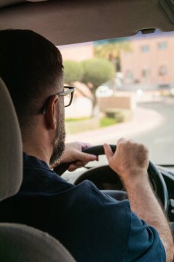 Banliyö sokaklarında gezinen, trafiğe odaklanan ve yolculuğun keyfini çıkarırken yol işaretlerini dikkatle izleyen bir sürücü.