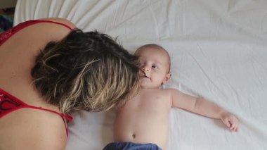 4 aylık bebek annesiyle nişanlanıyor, hassas iletişim anları sergiliyor ve beyaz bir yatak örtüsünde bağ kuruyor.