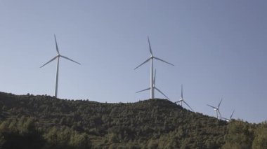 Rüzgar türbinleri tepenin üstünde sorunsuzca dönüyor. Temiz zemine karşı dönen pervanelerle yenilenebilir temiz enerji üretiyor.
