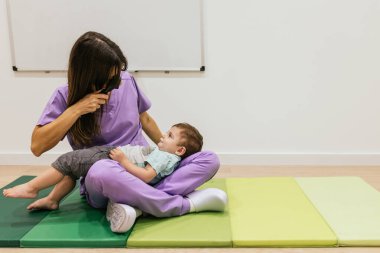 Doktor, muayene odasında genç bir çocuğun gözlerini incelemek için retinoskop kullanıyor.