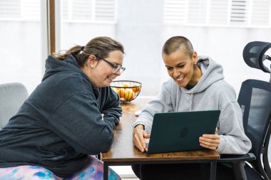 Beslenme uzmanı ve müvekkil danışma sırasında bir dizüstü bilgisayarla gülümsüyor ve etkileşime giriyorlar.