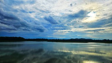 Alke yüzeyinde bulutlu bir günde akşam gökyüzünün yansıması. .