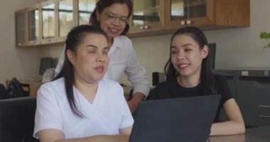 Asian women co-workers in workplace including person with blindness disability using laptop computer with screen reader program for visual impairment people. Disability inclusion at work concepts.