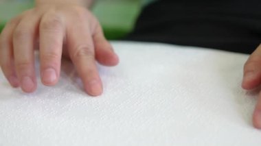 Close-up hand of person woman with blindness disability  moving fingers reading Braille book studying in creative library. Braille is a system of raised dots that can be read with the fingers