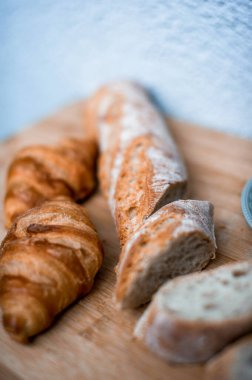 Tam tahıllı ekmek mutfak ahşap tabağına konmuş ve şefin elinde altın bıçak var. Masanın üzerinde taze ekmek var. Mutfak masasında taze ekmek sağlıklı beslenme ve geleneksel fırın konsepti