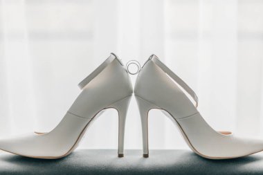 Beautiful wedding ring on the bride's white shoes. Jewelry and two gold wedding rings on a white background. Wedding concept.