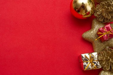 Kırmızı arkaplanda çeşitli altın noel süsleri