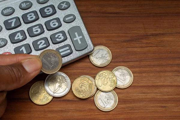 Ręka Trzymająca Monetę Euro Pobliżu Kalkulatora — Zdjęcie stockowe